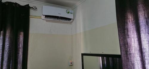 a tv on the wall of a room with purple curtains at EAGLE WEAVERS NEST in Livingstone