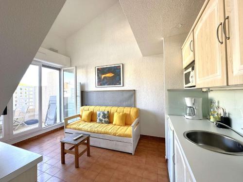 un salon avec un canapé jaune dans une cuisine dans l'établissement HYEVASS Studio pour 4 personnes proche de la plage des Salins situé à Hyères, à Hyères