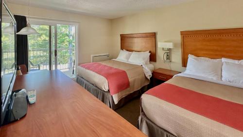 a hotel room with two beds and a desk at Bruce Anchor Motel in Tobermory