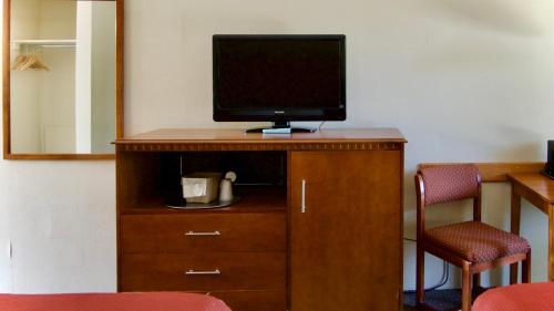 a television on top of a wooden dresser with a mirror at Bruce Anchor Motel in Tobermory