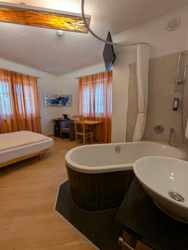 a bathroom with a tub and a sink and a bed at Rising Sun in Zermatt