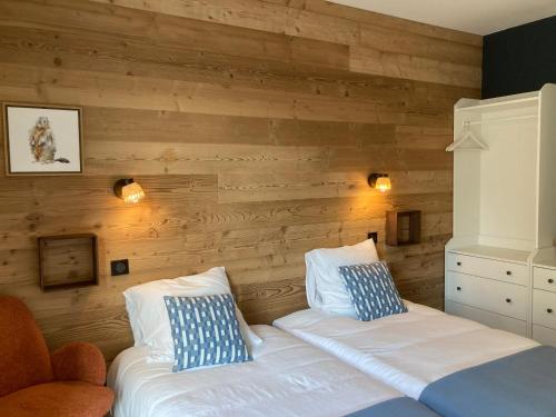 a bedroom with two beds and a wooden wall at Le chalet Paula in Agos-Vidalos
