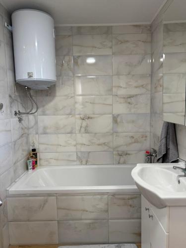 a bathroom with a white tub and a sink at Vikendica Šššuma in Srbac