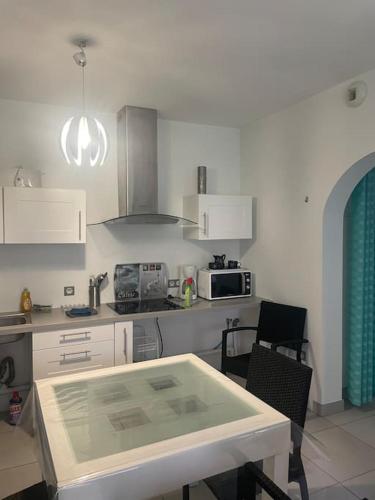 une cuisine avec une table et un comptoir dans l'établissement Bleu Lagon-T2 en RDC proche centre ville avec terrasse labellisé PMR, à Salies-de-Béarn