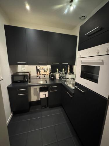 une cuisine avec des armoires noires et un four à plaques de cuisson dans l'établissement Boulevard des Belges, Cœur du sixième, à Lyon