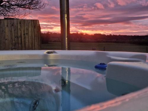 a bath tub with a sunset in the background at Bowland Breaks-A Luxury Barn Conversion with Optional Hot Tub, Log burner and countryside views in Longridge
