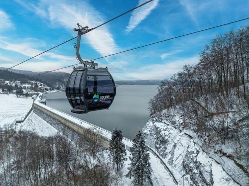 a ski lift over a snow covered mountain with a lake at Chata w Bieszczadzie apartamenty i domki z basenem Bieszczady in Polańczyk