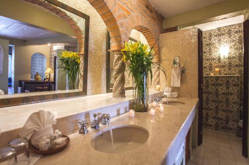 a bathroom with a sink with a vase of flowers at Quinta Maria Cortez Beach Hotel in Puerto Vallarta