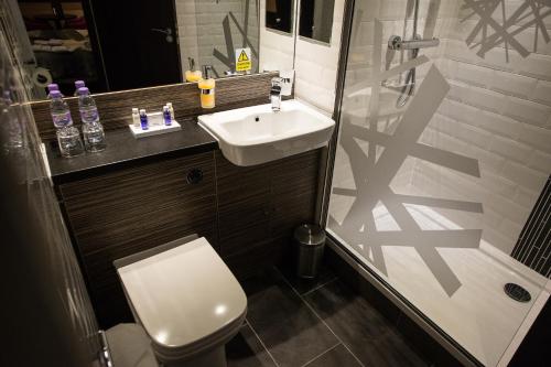 a bathroom with a sink and a toilet and a shower at Mondo Hotel in Coatbridge