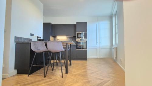 une cuisine avec deux tabourets de bar et un comptoir dans l'établissement Appartement Le Napoléon Rouen Hypercentre, à Rouen