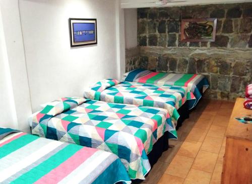 a row of beds in a room with a tv at Hotel Porto Bello in San Pedro La Laguna