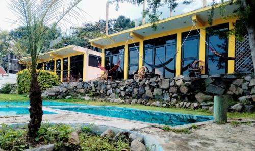 a house with a stone wall and a swimming pool at Hotel Porto Bello in San Pedro La Laguna