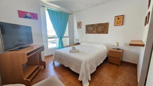 a bedroom with a bed and a flat screen tv at El Fortín de la playa by Sanlúcar Housing in Sanlúcar de Barrameda