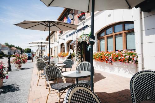 an outdoor cafe with tables and chairs and umbrellas at Armes de Champagne in Châlons-en-Champagne