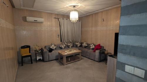 een woonkamer met een bank en een tafel bij Appartement meublée in Kenitra