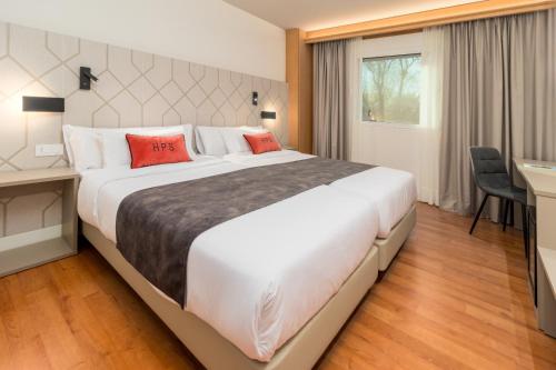 a bedroom with a large white bed with red pillows at Hotel Puerta Santander in Santander