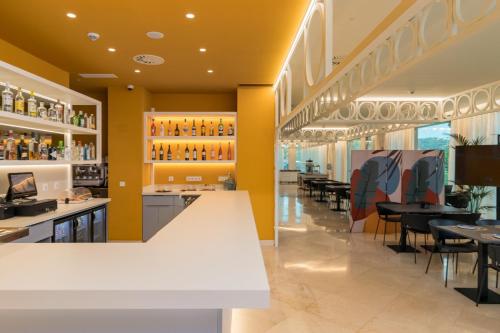 a restaurant with yellow walls and tables and chairs at Hotel Puerta Santander in Santander