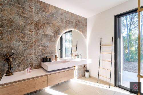 une salle de bain avec un lavabo et un miroir dans l'établissement Biscarrosse Lac Villa de charme PMR climatisée avec vue sur le golf pour 8/10 personnes, à Biscarrosse