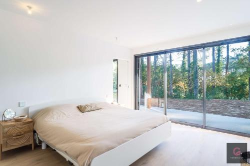 une chambre avec un lit et une grande fenêtre dans l'établissement Biscarrosse Lac Villa de charme PMR climatisée avec vue sur le golf pour 8/10 personnes, à Biscarrosse