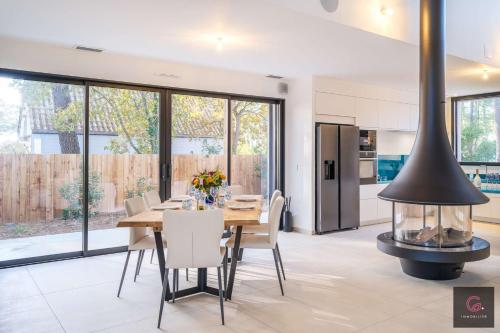 une cuisine et une salle à manger avec une cheminée dans une maison dans l'établissement Biscarrosse Lac Villa de charme PMR climatisée avec vue sur le golf pour 8/10 personnes, à Biscarrosse