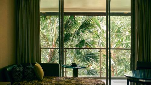 a bedroom with a large window with a palm tree outside at RIMBA by AYANA Bali in Jimbaran