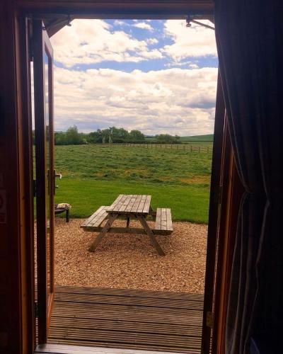an open door to a picnic table in a field at Millside by Wigwam Holidays in Grantham