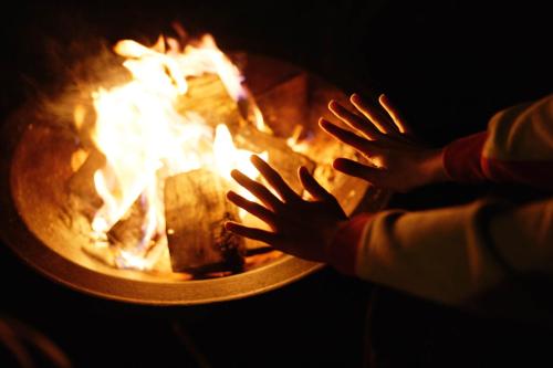 a person with their hands around a fire at Millside by Wigwam Holidays in Grantham
