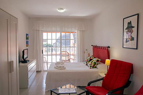 a living room with a red chair and a table at Apartamentos Bellavista Gomera in Playa de Santiago