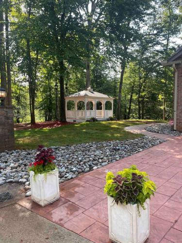a gazebo in the middle of a yard with two plants at Whisper Chateau Weddings Reunions Groups 75 Plus in Greensboro