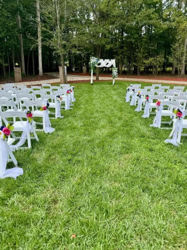 a row of white chairs sitting in the grass at Whisper Chateau Weddings Reunions Groups 75 Plus in Greensboro