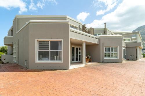 a large house with a brick driveway in front of it at Beachfront Villa Sea Breeze Hout Bay Cape Town in Hout Bay
