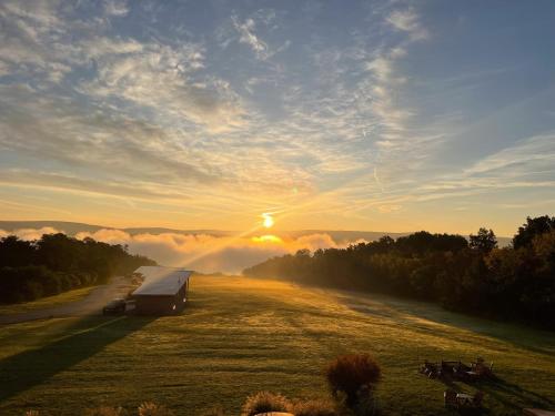 a barn in a field with the sunset in the background at Lakeside Resort in Watkins Glen