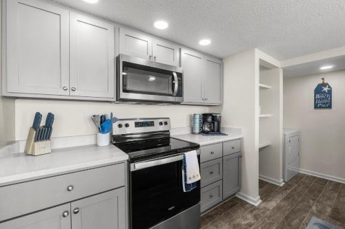 a kitchen with white cabinets and a black stove top oven at Sandpiper Beacon Beach Resort in Panama City Beach