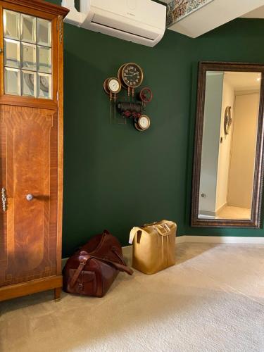 a room with a green wall with a clock and a purse at Au Petit Manoir in Socx