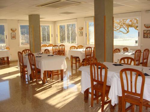 a dining room with white tables and wooden chairs at Hotel Del Llac in Coll de Nargó