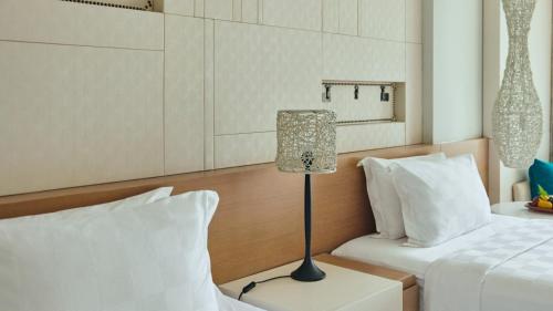 a hotel room with two beds and a lamp at RIMBA by AYANA Bali in Jimbaran
