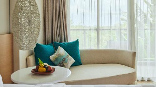 a living room with a couch and a bowl of fruit on a table at RIMBA by AYANA Bali in Jimbaran