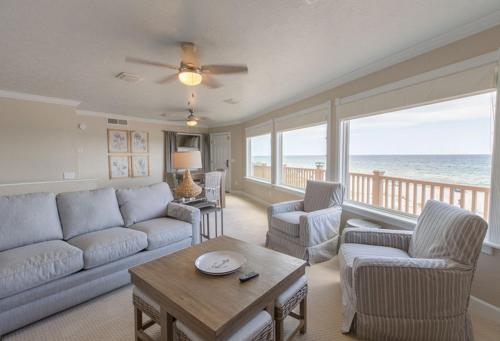a living room with a couch and chairs and the ocean at Sandpiper Beacon Beach Resort in Panama City Beach
