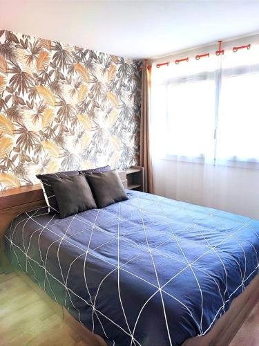 - une chambre avec un lit bleu et un mur fleuri dans l'établissement appartement spacieux 3 chambres, à Savigny-sur-Orge