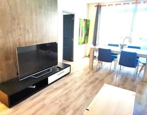 - un salon avec une grande télévision et une table avec des chaises dans l'établissement appartement spacieux 3 chambres, à Savigny-sur-Orge