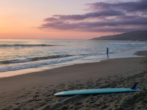 a person standing on a beach with a surfboard on the beach at Aourir Waves Surf House in Aourir