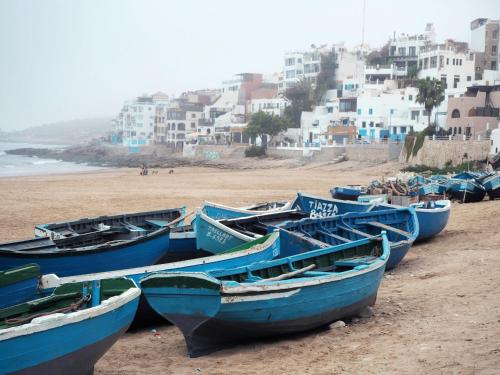 a group of blue boats sitting on the beach at Aourir Waves Surf House in Aourir