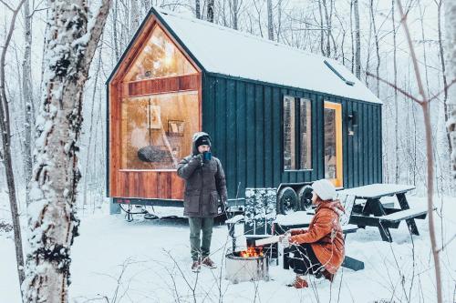 two people standing in the snow in front of a cabin at Lumen Nature Retreat in Woodstock