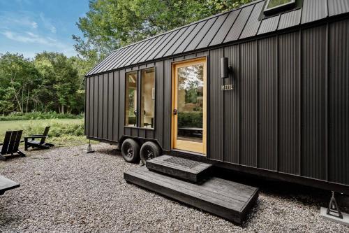 a black tiny house sitting on top of gravel at Lumen Nature Retreat in Woodstock