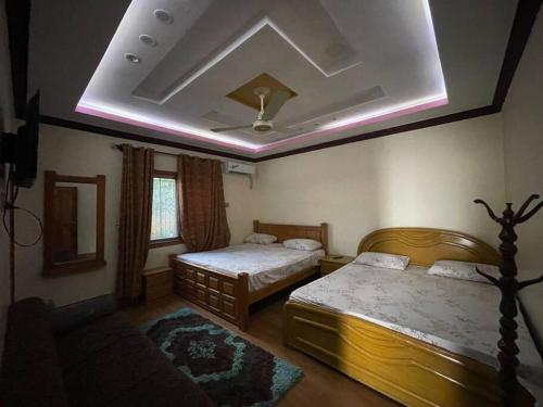 a bedroom with two beds and a ceiling at Eagles Nest Muzaffarabad in Muzaffarabad
