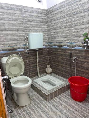a bathroom with a toilet and a bucket at Eagles Nest Muzaffarabad in Muzaffarabad