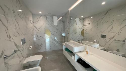 a bathroom with a sink and a toilet and a mirror at Hortas Residence 13 in Funchal