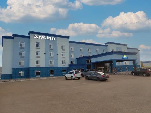 Un gran edificio con coches aparcados en un estacionamiento. en Days Inn & Suites by Wyndham Fort Saskatchewan, en Fort Saskatchewan