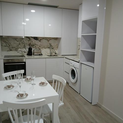a white kitchen with a white table and chairs at CasAmalia 54 in Viana do Castelo