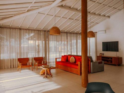 a living room with a red couch and a tv at Casa Caetano - Peninsula de Maraú - Taipus de Fora in Taipu